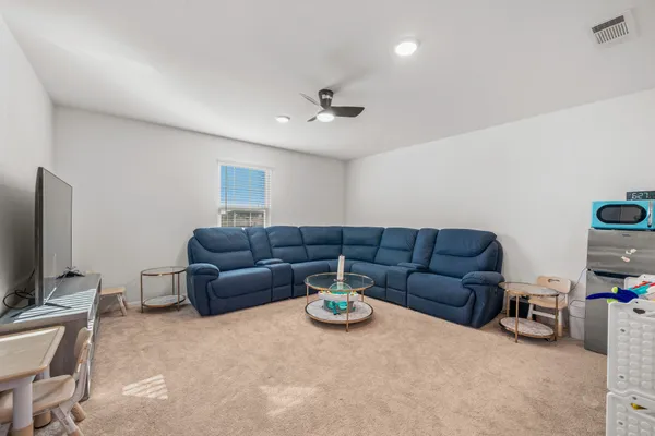 a living room with furniture a ceiling fan and a flat screen tv