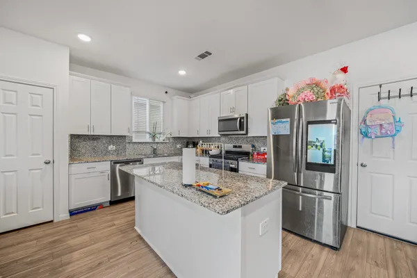 a kitchen with kitchen island granite countertop a sink cabinets and stainless steel appliances