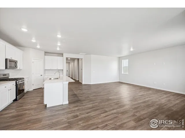 a kitchen with stainless steel appliances granite countertop a sink a stove a microwave a sink a refrigerator and white cabinets