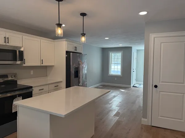 a view of a kitchen with a sink and dishwasher a refrigerator with wooden floor