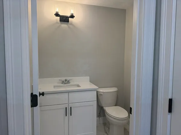 a bathroom with a toilet sink vanity and mirror
