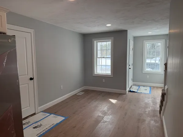 a view of an empty room with wooden floor and a window