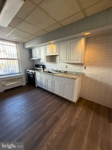 a kitchen with stainless steel appliances granite countertop a sink cabinets wooden floor and a window