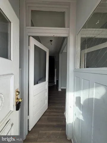 a view of a hallway with wooden floor and a living room