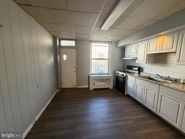 a kitchen with granite countertop lots of white cabinets and wooden floor