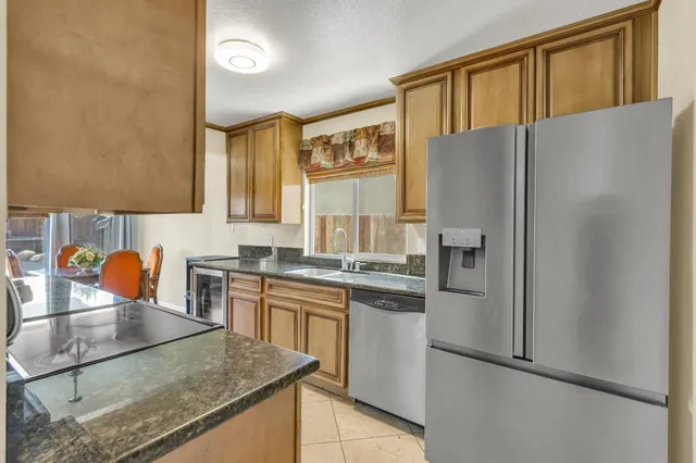 a kitchen with stainless steel appliances granite countertop a refrigerator a stove and a sink with large cabinets
