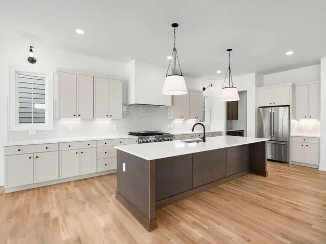 a large kitchen with granite countertop a stove a sink a center island and stainless steel appliances