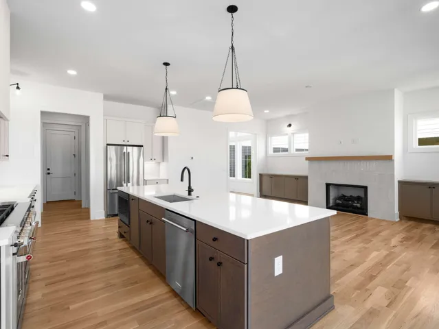 a large kitchen with kitchen island a stove a sink a center island and wooden floor