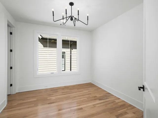a view of empty room with wooden floor and window