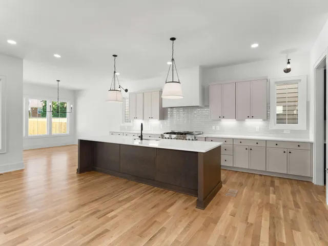 a large kitchen with kitchen island wooden floors white cabinets and stainless steel appliances