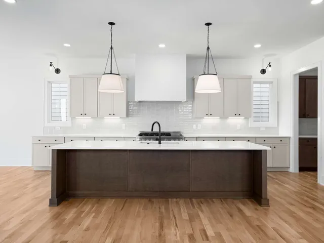 a large kitchen with stainless steel appliances granite countertop a sink a stove a refrigerator and a wooden floor