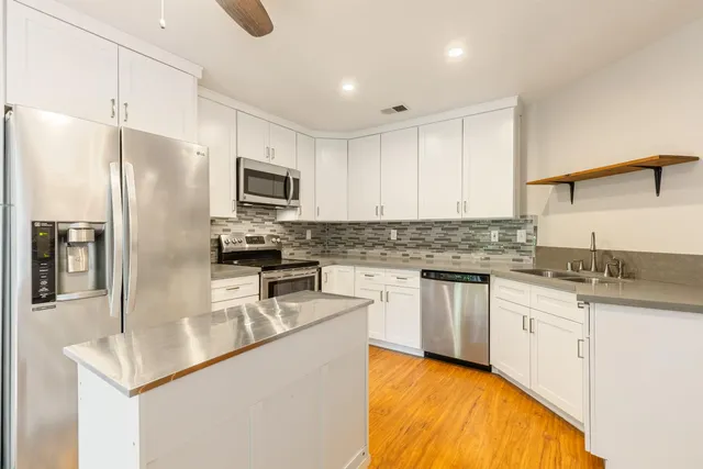 a kitchen with granite countertop a refrigerator stove top oven and sink
