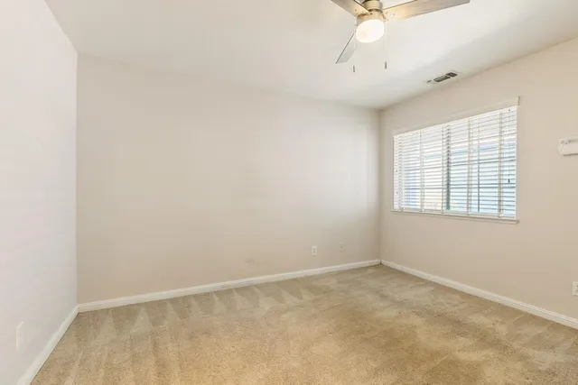 an empty room with a window and a fan