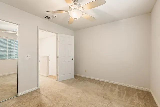 an empty room with chandelier fan and closet area