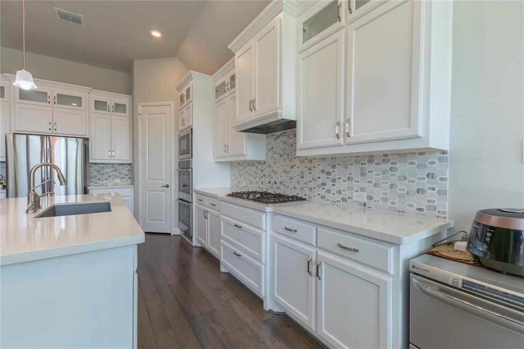 3920 Bentgrass Road Plano, TX 75023 - Photo 14 of 30 a kitchen with stainless steel appliances white cabinets and a stove top oven