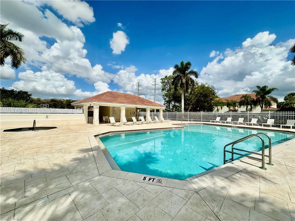 996 Hampton Circle, Unit 71 Naples, FL 34105 - Photo 25 of 30 a view of a swimming pool with a lawn chairs under an umbrella