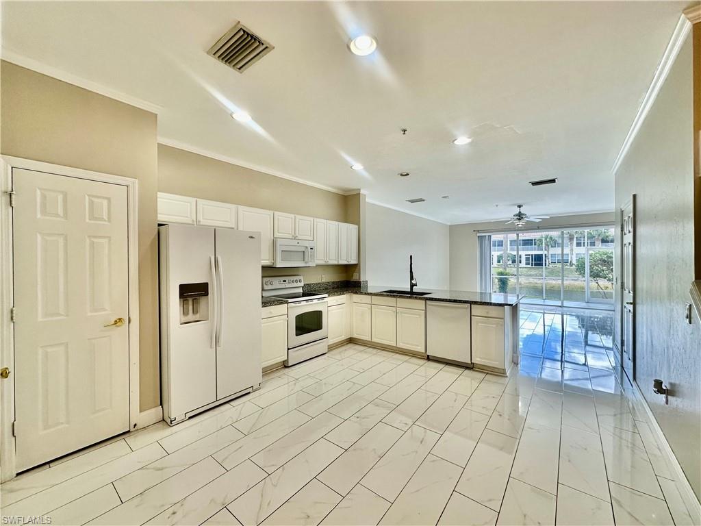 996 Hampton Circle, Unit 71 Naples, FL 34105 - Photo 3 of 30 a large kitchen with stainless steel appliances kitchen island granite countertop a refrigerator and a stove top oven