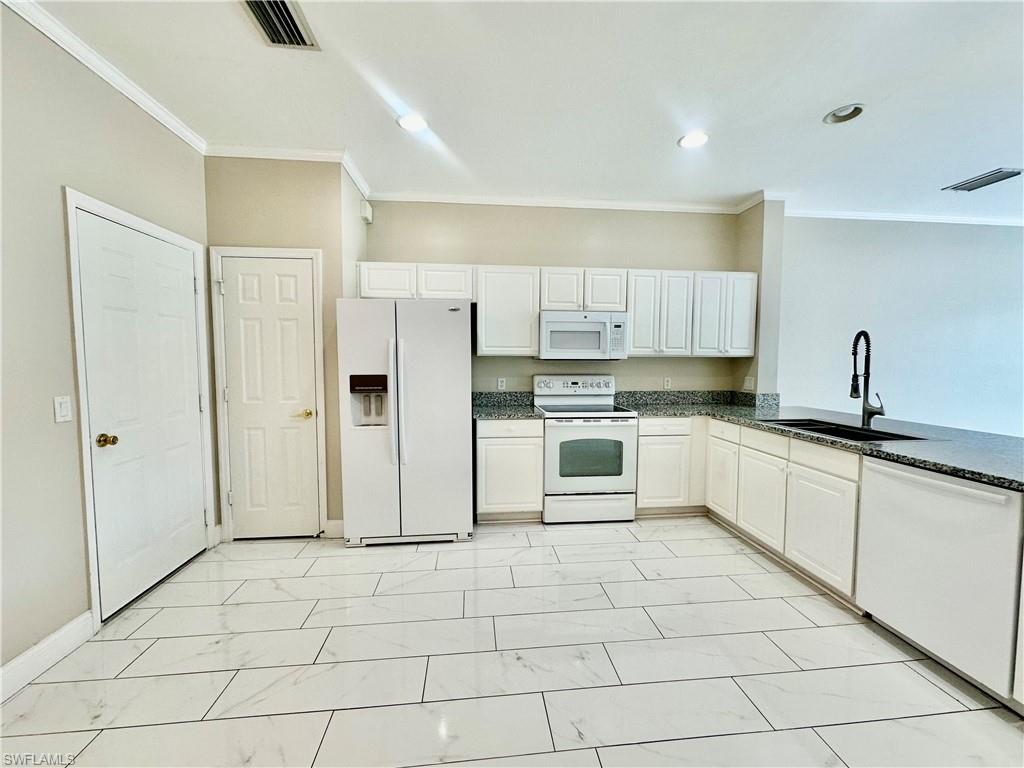 996 Hampton Circle, Unit 71 Naples, FL 34105 - Photo 4 of 30 a large white kitchen with cabinets and stainless steel appliances