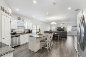a view of a dining room and livingroom with furniture wooden floor a chandelier