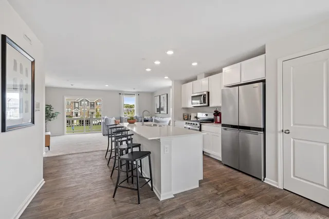 a kitchen with stainless steel appliances a refrigerator a stove a dining table and chairs