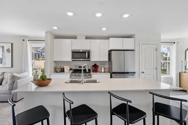 a kitchen with a dining table chairs refrigerator and microwave