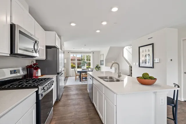 a kitchen with stainless steel appliances a stove a sink a oven a dining table and chairs