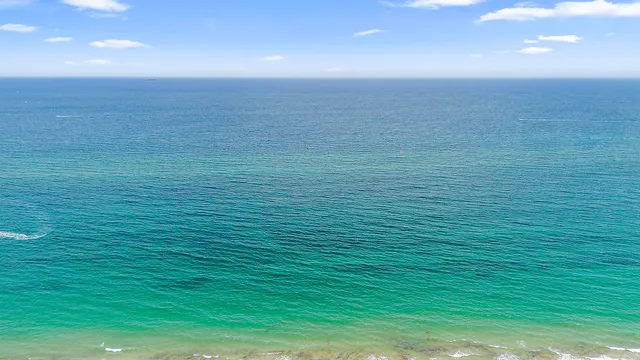 an aerial view of a city with lots of residential buildings ocean and mountain view in back