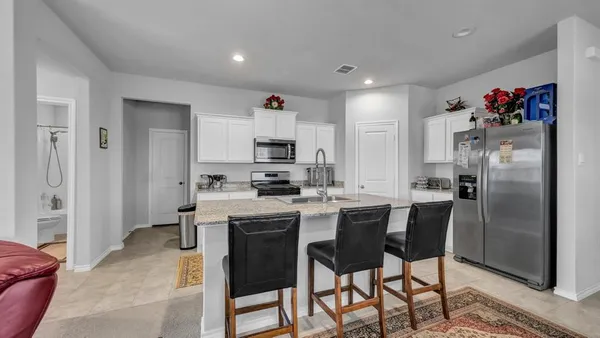 a kitchen with stainless steel appliances a white refrigerator stove a sink and chairs
