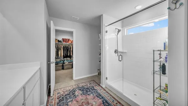 a view of a hallway with wooden floor and a bathroom
