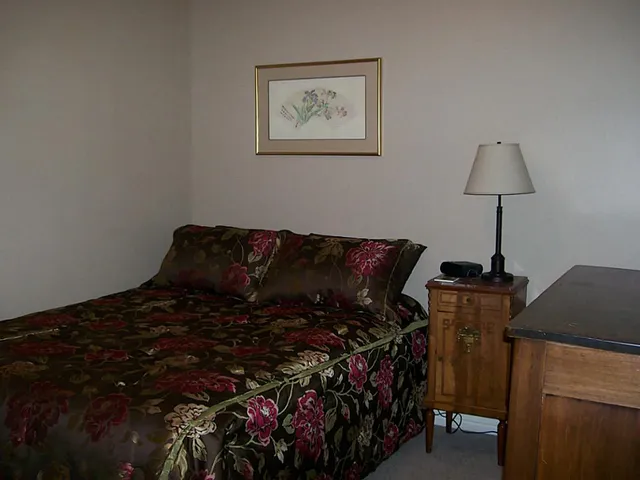 a bed sitting in a bedroom next to a window and a lamp