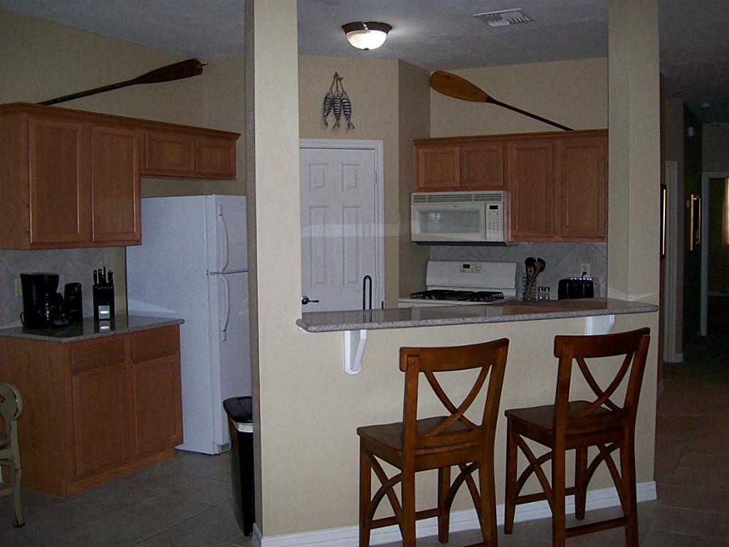 811 Bradford Avenue, Unit 5B Kemah, TX 77565 - Photo 8 of 22 a kitchen with stainless steel appliances granite countertop a refrigerator a sink and wooden cabinets
