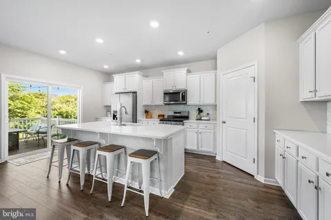 a kitchen with stainless steel appliances granite countertop a table chairs sink refrigerator and cabinets
