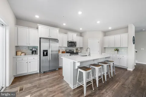 a kitchen with stainless steel appliances a refrigerator a stove top oven and a center island with wooden floor