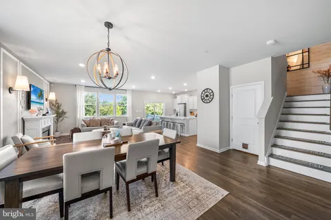 a view of a dining room and livingroom with furniture wooden floor a rug a painting and a chandelier