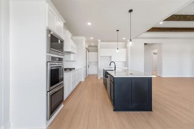 a kitchen with stainless steel appliances granite countertop a sink a stove and a wooden floors