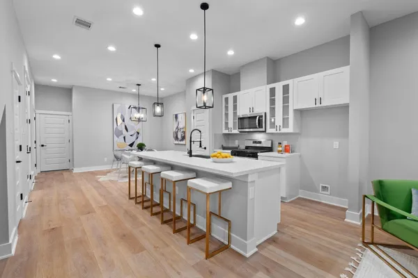 a kitchen with stainless steel appliances granite countertop a refrigerator a stove top oven a sink dishwasher and a dining table with wooden floor