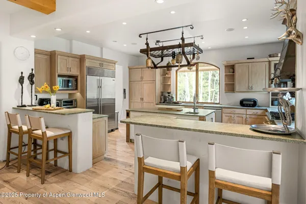 a kitchen with stainless steel appliances a dining table chairs sink and cabinets