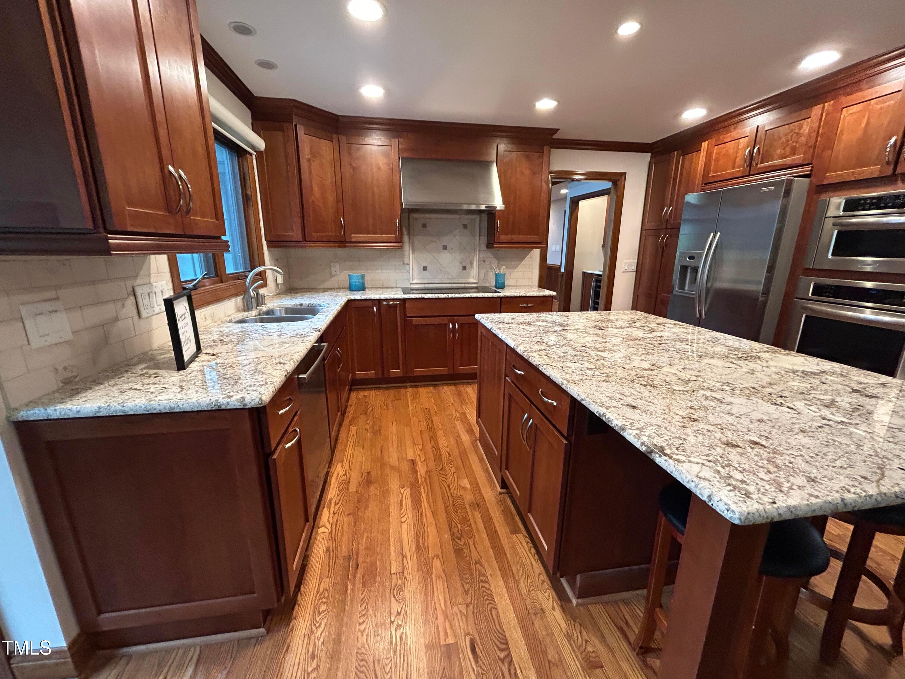 106 Springbrook Place Cary, NC 27518 - Photo 11 of 49 a kitchen with kitchen island granite countertop wooden cabinets a refrigerator and a sink