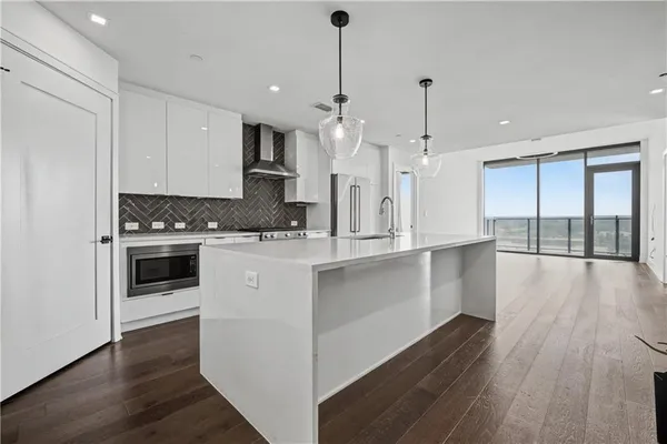 a kitchen with granite countertop a stove top oven a sink dishwasher a kitchen island with wooden floor and cabinets