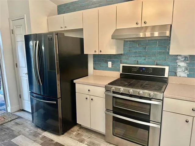 a kitchen with metallic refrigerator and a stove top oven