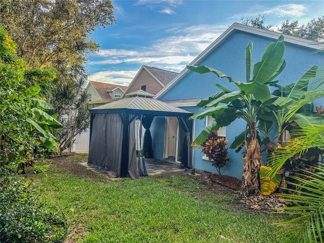 a view of a wooden house with a big yard and large trees