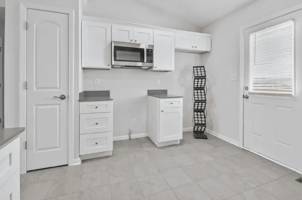 a view of kitchen and refrigerator in white cabinet