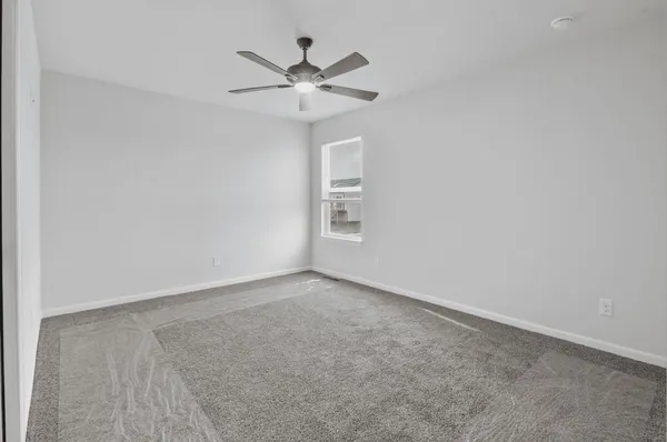 an empty room with a window and a chandelier fan