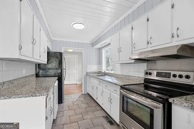 a kitchen with granite countertop a stove sink and cabinets