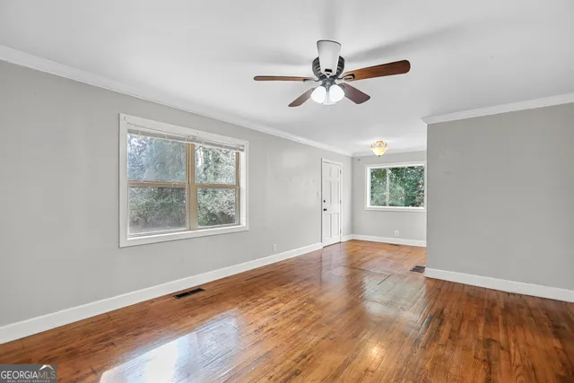 a view of an empty room with wooden floor and a window