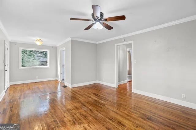 a view of an empty room with window and wooden floor