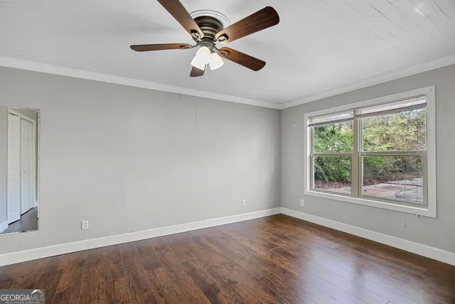 an empty room with wooden floor fan and windows