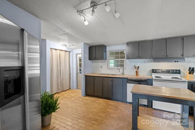 a kitchen with stainless steel appliances granite countertop a stove top oven a sink refrigerator and microwave