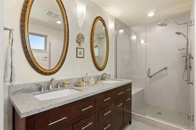 a bathroom with a granite countertop double vanity mirror and a sink