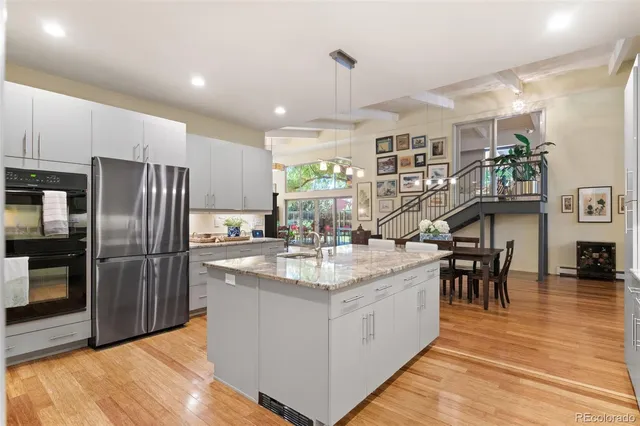 a kitchen with stainless steel appliances granite countertop a table chairs and a refrigerator